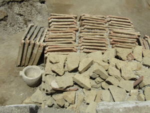 Stacks of building materials found in the atrium of the Pompeii town house, including stone blocks, tuff, orderly rows of roof tiles. Image courtesy of Italian Ministry of Culture